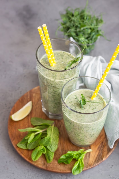 Foto smoothie saudável verde em copos com ingredientes na placa de madeira