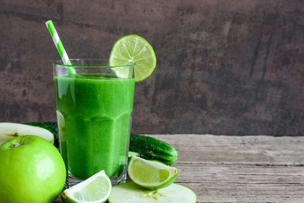 Smoothie saudável verde em um copo com espinafre, maçã, pepino e limão com um canudo. bebida desintoxicante