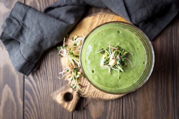 Foto smoothie vegan verde com espinafre e sementes germinadas em uma superfície de madeira escura