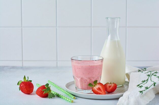 Smoothie vegetariano saudável de morango com bagas em fundo de concreto cinza ou branco