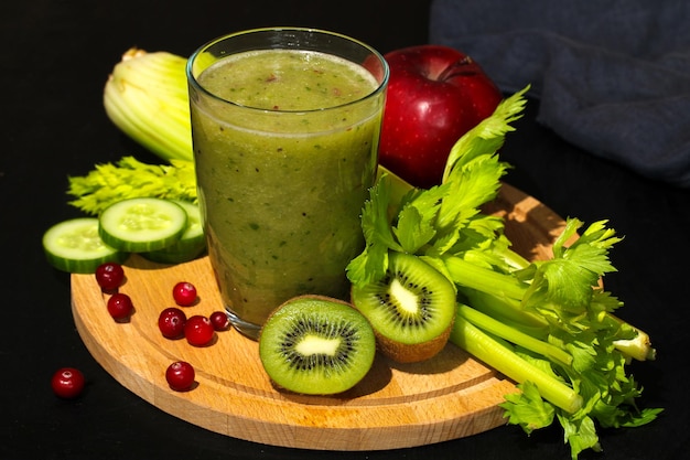 Smoothie verde cercado de frutas e legumes frescos que promovem um estilo de vida saudável
