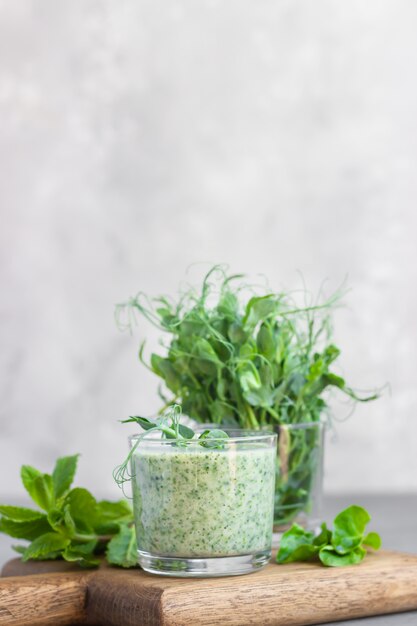 Smoothie verde com espinafre, hortelã e jovens brotam microgreen em uma placa de madeira