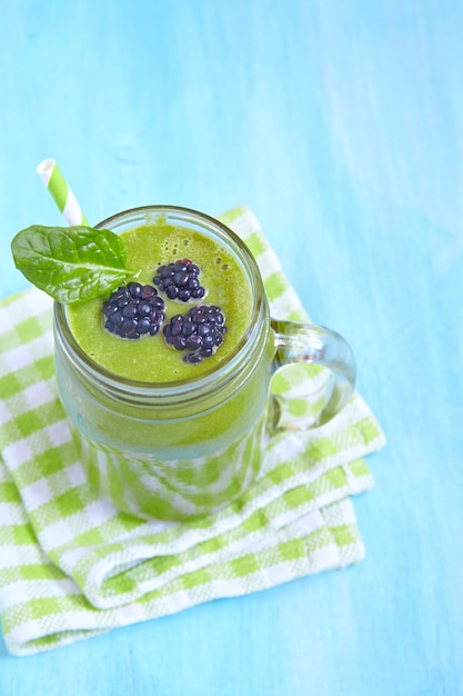 Smoothie verde de espinafre coberto com folhas e amora