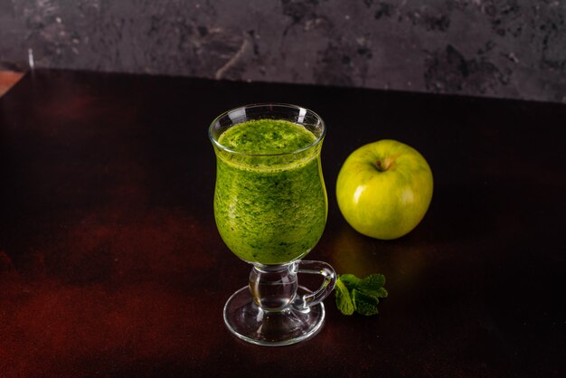 Smoothie verde de la manzana del jengibre en fondo concreto.