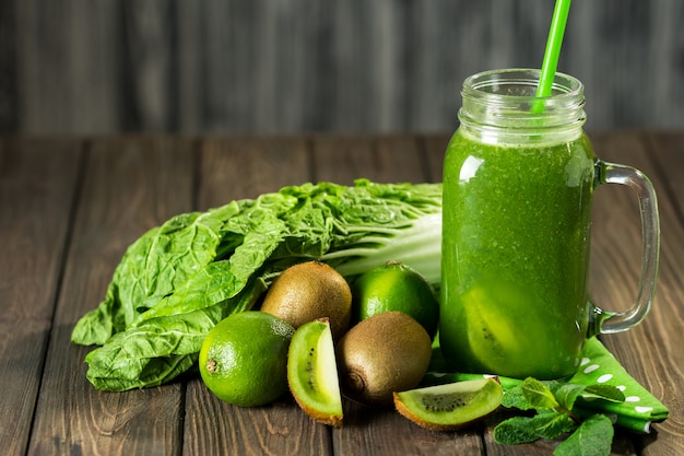 Smoothie verde misturado com ingredientes na mesa de madeira