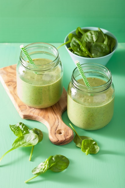 Smoothie verde saudável com banana de manga de espinafre em potes de vidro