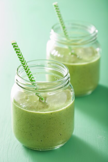 Smoothie verde saudável com banana de manga de espinafre em potes de vidro