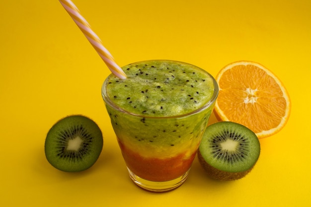 Smoothies coloridos com kiwi, laranja e morango no fundo amarelo