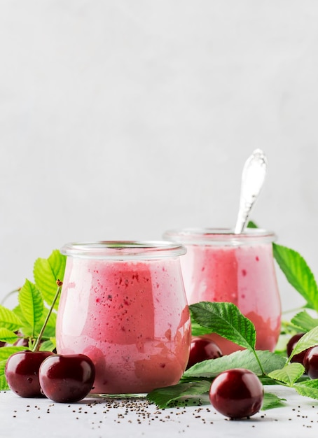 Smoothies de cereja rosa com frutas vermelhas frescas e sementes de chia folhas verdes lugar de fundo de cozinha de pedra branca para foco seletivo de texto