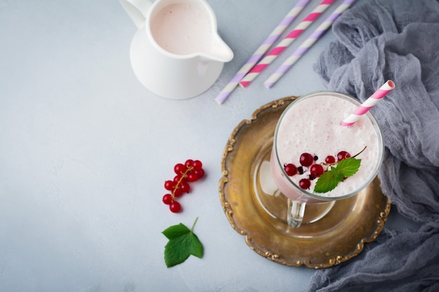Smoothies de iogurte de groselha, milkshake em um copo de vidro sobre um fundo cinza de concreto.