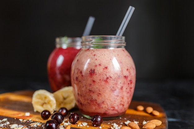 Smoothies preparados na hora de banana com romã e banana com amora em garrafa. Dieta, estilo de vida saudável