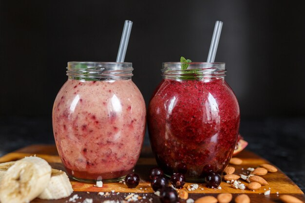 Smoothies preparados na hora de banana com romã e banana com amora em garrafa. Dieta, estilo de vida saudável