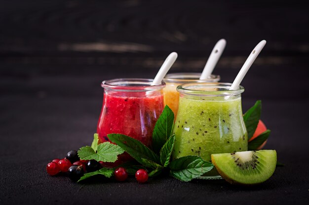 Smoothies saudáveis frescos de frutas diferentes em uma mesa escura. Menu de dieta. Nutrição apropriada.