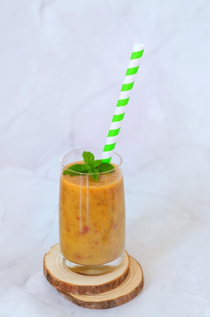 smoothies saudáveis frescos em um copo feito de pêssego, banana, frutas com hortelã. bebida desintoxicante saudável