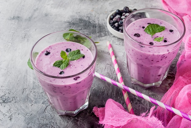 Smoothies von Blaubeeren und Banane in Gläsern und Zutaten auf einem Holztisch