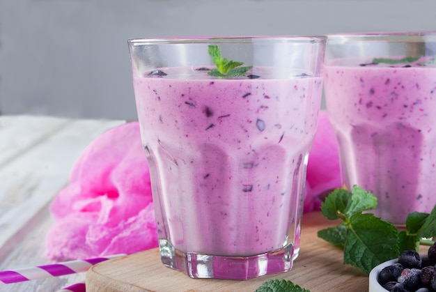 Smoothies von Blaubeeren und Banane in Gläsern und Zutaten auf einem Holztisch