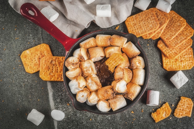 Smores de interior, smores al horno sumergidos en una sartén de hierro fundido con galletas Graham