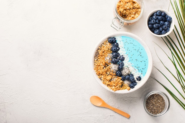 Smothie azul en un tazón con granola y bayas