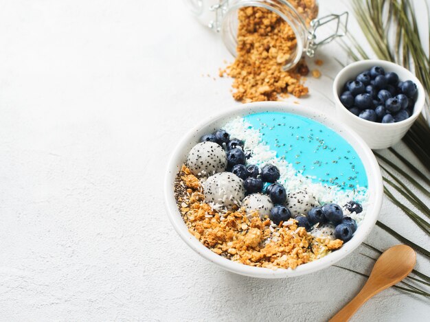 Smothie azul en un tazón con granola y bayas