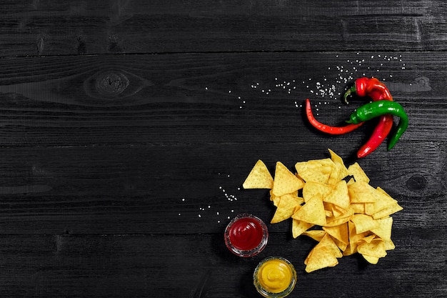 Snack für Partychips Nachos mit Saucen Tomatenketchup Senf auf einem schwarzen Hintergrund Draufsicht Kopie...