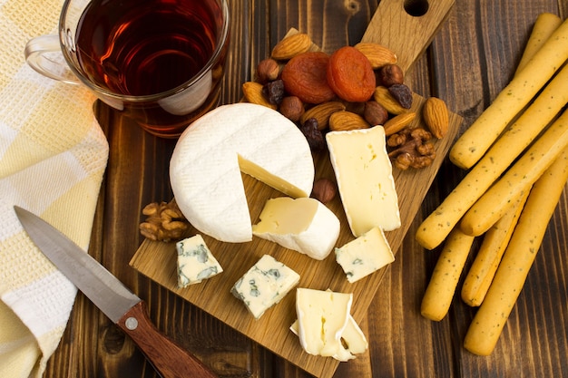 Snack mit Käse und Brotstangen auf dem braunen Holzhintergrund. Blick von oben.