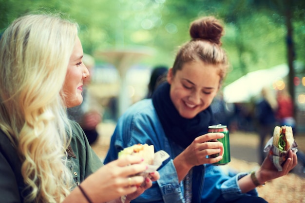 Snack mulheres e festival de música com amigos conversa e felicidade com alegria e ligação juntos Pessoas ao ar livre e meninas com fast food e takeaway com férias de verão ou concerto com cultura