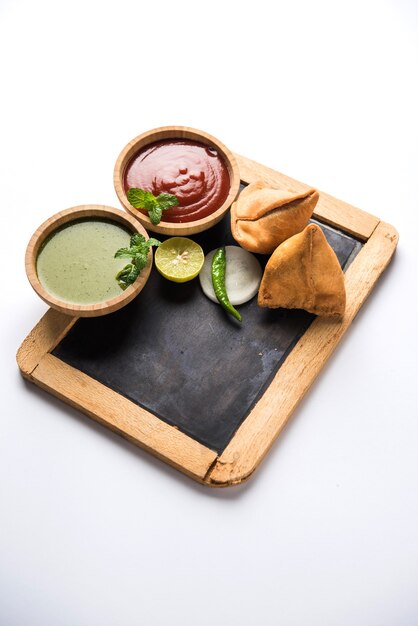 Snack Samosa servido com lousa ou ardósia para texto, servido com ketchup e chutney de menta