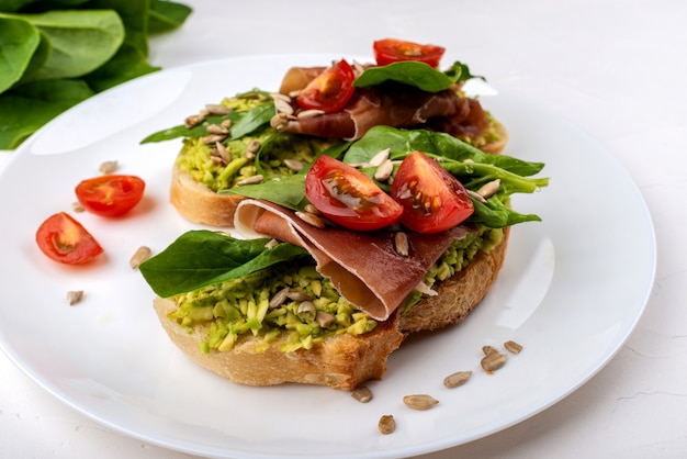 Snack-Sandwiches mit Jamon, Avocado, Tomaten und Blattsalat.