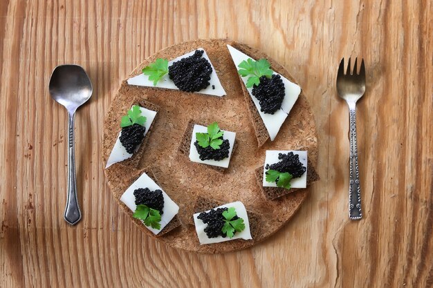 Snack schwarzer Kaviar auf einem hölzernen braunen Hintergrund