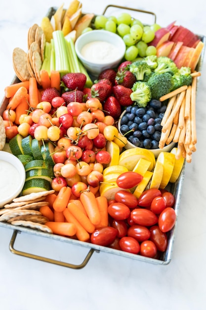 Foto snackboard mit frischem obst, gemüse, crackern und dips.