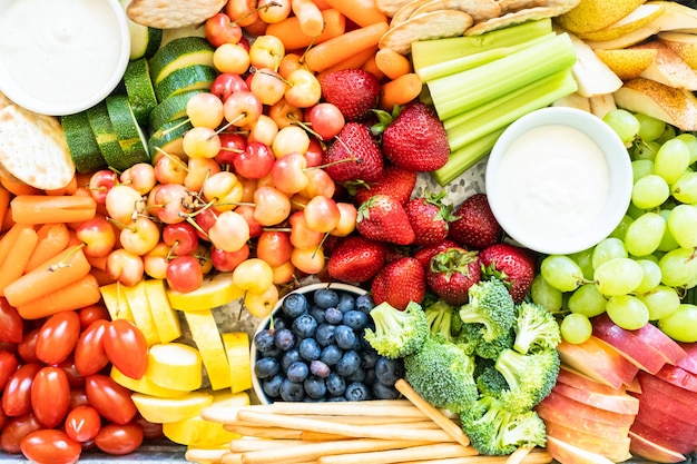 Snackbrett mit frischem Obst, Gemüse, Crackern und Dips.