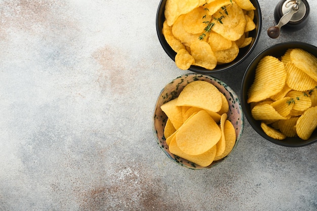 Snacks Ungesundes Essen Alle klassischen Kartoffelsnacks mit Erdnuss-Popcorn und Zwiebelringen und gesalzenen Brezeln in Schalenplatten auf grauem Betongrund Ungesundes Essen für Figurherzhautzähne