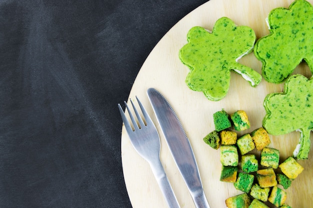 Snacks von grüner Farbe mit einer Gabel und einem Messer. Arbeitsraum, das Konzept von St. Patrick