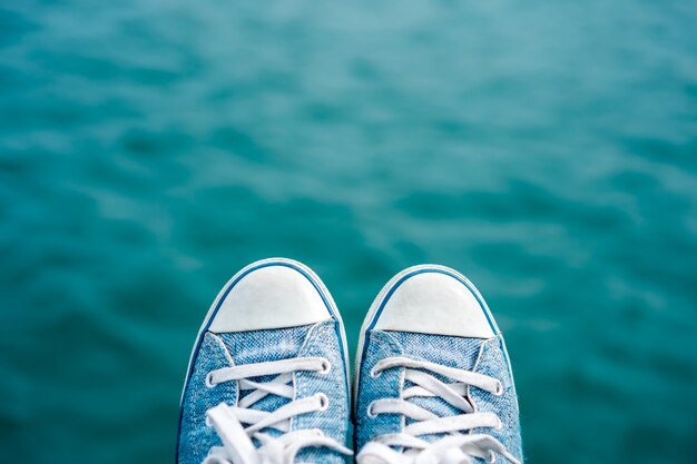 Sneaker Schuh auf verschwommenem blauen Ozean mit Bokeh.