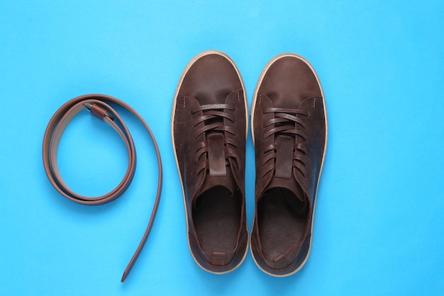 Foto sneakers de couro castanho e cinto para homens com fundo azul