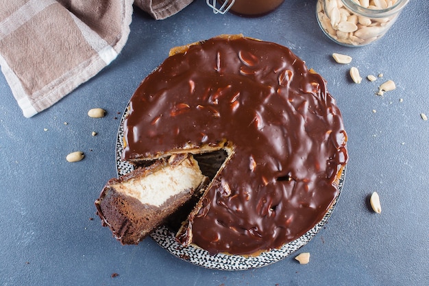 Snickers de tarta de queso con caramelo, turrón y pastel de cacahuate sobre fondo de hormigón azul