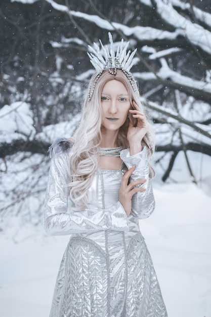 Snow Queen cosplay en el fondo del bosque de invierno Fotografía artística