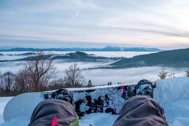 Snowboarder apreciando a vista do pôr do sol acima das montanhas