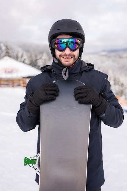 Snowboarder de homem fica com snowboard. retrato do close up.