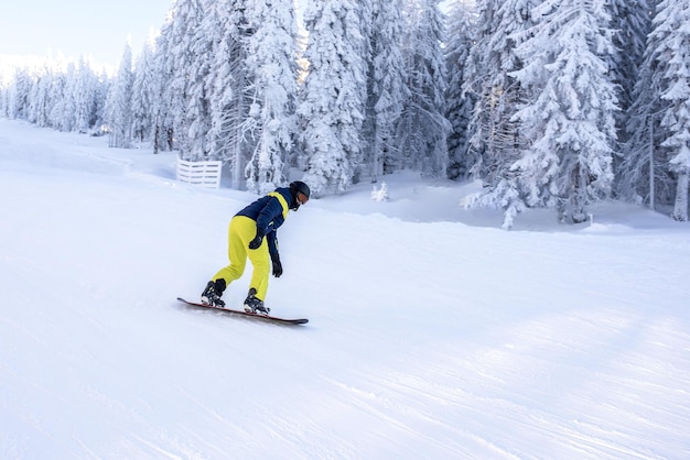 Snowboarder, der im Bergresort den Hügel hinunterfährt