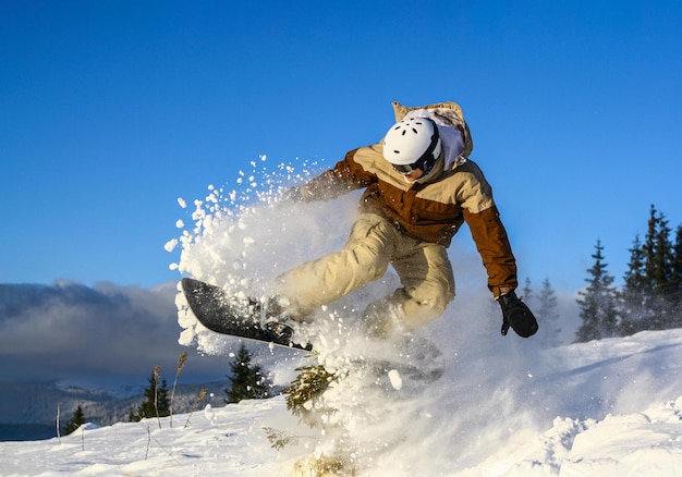 Snowboarder fazendo truque de estilo livre em um dia ensolarado sob o céu azul em uma neve em pó