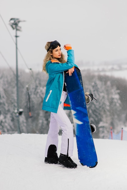 Snowboarder feliz posando de óculos escuros com uma prancha de snowboard