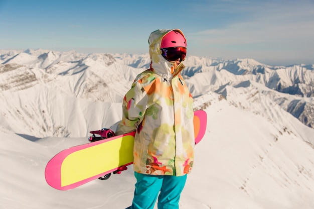 Foto snowboarder femenino en ropa deportiva de pie en la cima de la montaña