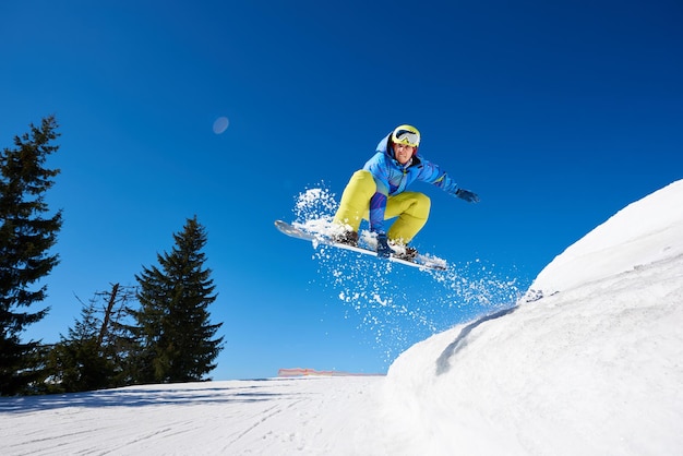 Snowboarder freerider springt bergab in der luft auf kopierraumhintergrund des blauen himmels und des weißen schnees