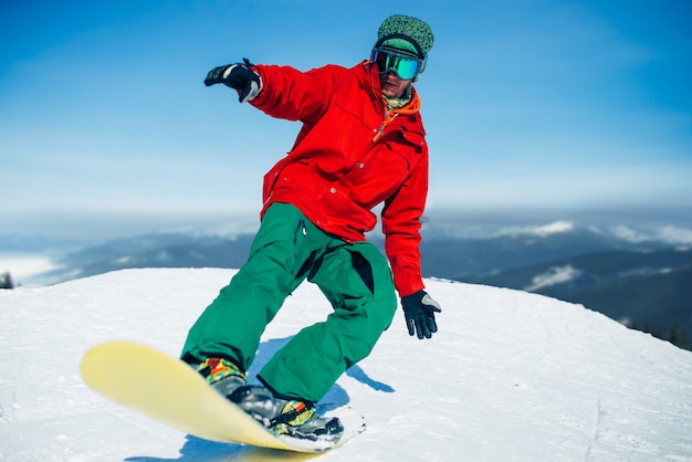 Snowboarder en gafas posa con tablero en manos