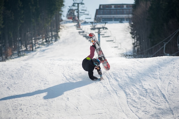 Snowboarder im Moment auf die schneebedeckte Piste fallen