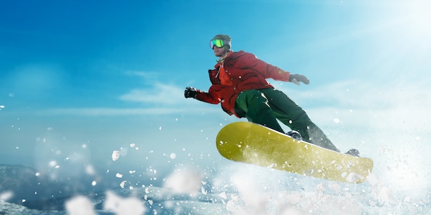 Foto snowboarder in brille macht einen sprung, sportler in aktion. aktiver wintersport, extremer lebensstil. snowboarden in den bergen