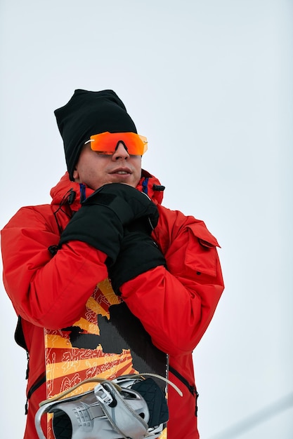 Snowboarder masculino em um terno vermelho andando na colina de neve com conceito de snowboard, esqui e snowboard.