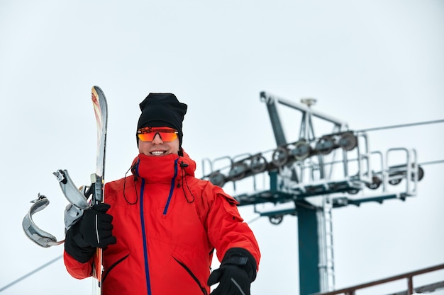 Snowboarder masculino con traje rojo caminando por la colina nevada con concepto de snowboard, esquí y snowboard.