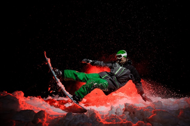 Snowboarder mujer vestida con una ropa deportiva verde realiza trucos en la ladera de la montaña